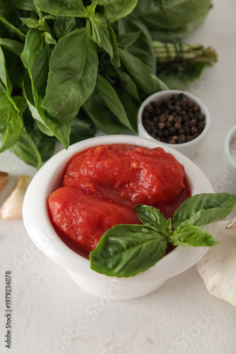 Bowl of canned tomatoes and spices on light background