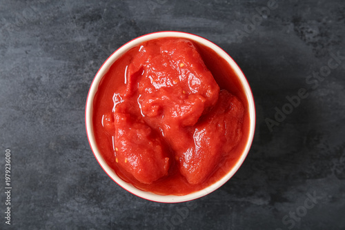 Bowl of canned tomatoes on dark background