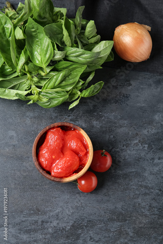 Bowl of canned tomatoes and basil on dark background