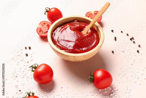 Bowl with tomato paste and fresh vegetables on light background