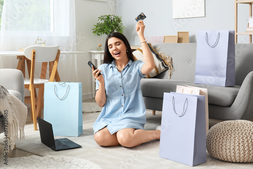 Young woman with credit card and mobile phone shopping online at home