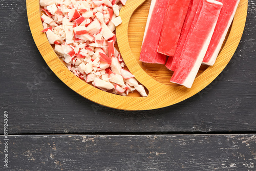 Plate with tasty crab sticks on dark wooden background, closeup