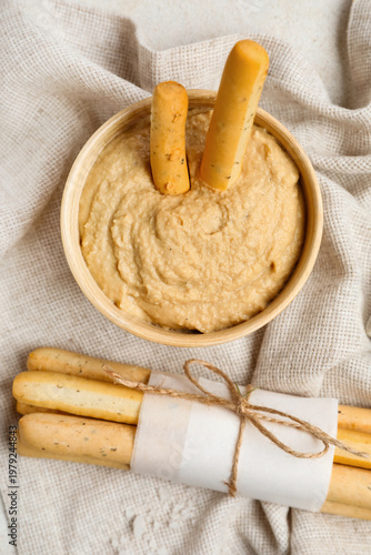 Bowl with tasty hummus and bunch of Italian Grissini on table