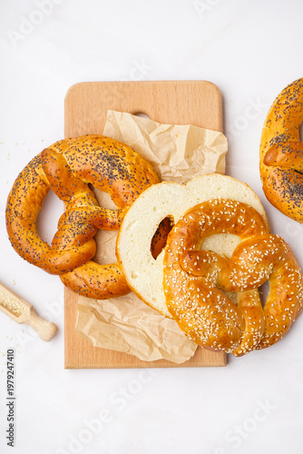 Wooden board with tasty pretzels on light background