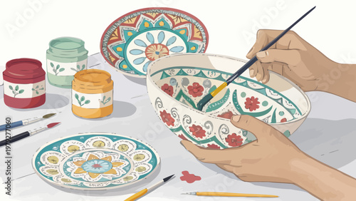 Hands painting colorful designs on ceramic bowls with a brush and paint jars on a table