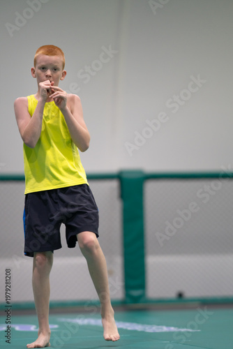 A red-haired teenager practices punches. A young man practices various punches. A boy trains on a wrestling mat. High quality photo