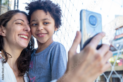Diverse mom and daughter smiling together on a selfie. Multiracial family concept.