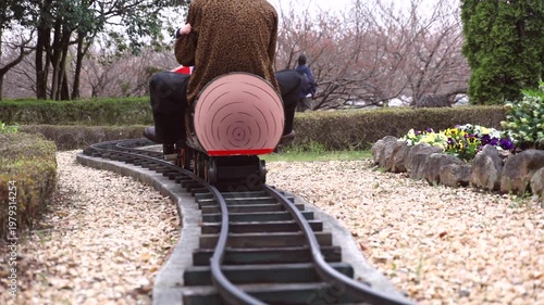 Slow motion of a child riding a miniature steam locomotive train at a park, close-up of wheels and movement.