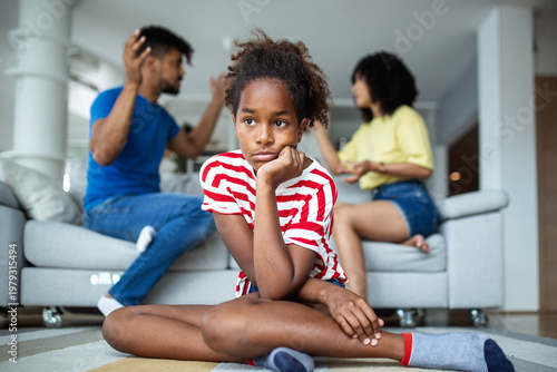 Bild auf Leinwand Unhappy African American kid looking away while parents have a heated argument in the background