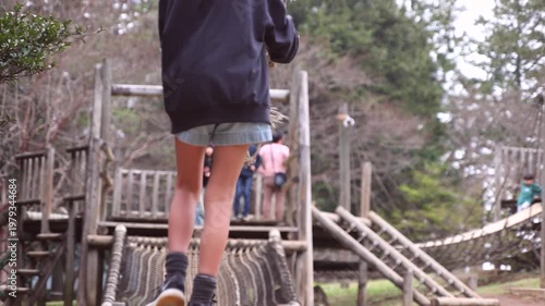 Slow motion of a boy playing on a zip line or rope swing at an outdoor adventure park, rear view.