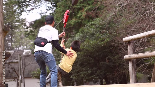 Slow motion of a boy playing on a zip line or rope swing at an outdoor adventure park, rear view.