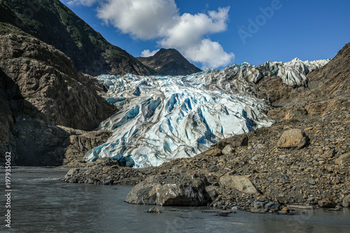 Massive Chilkat Glacier in Alaska towering above tranquil fjord waters with a small canoe in the foreground