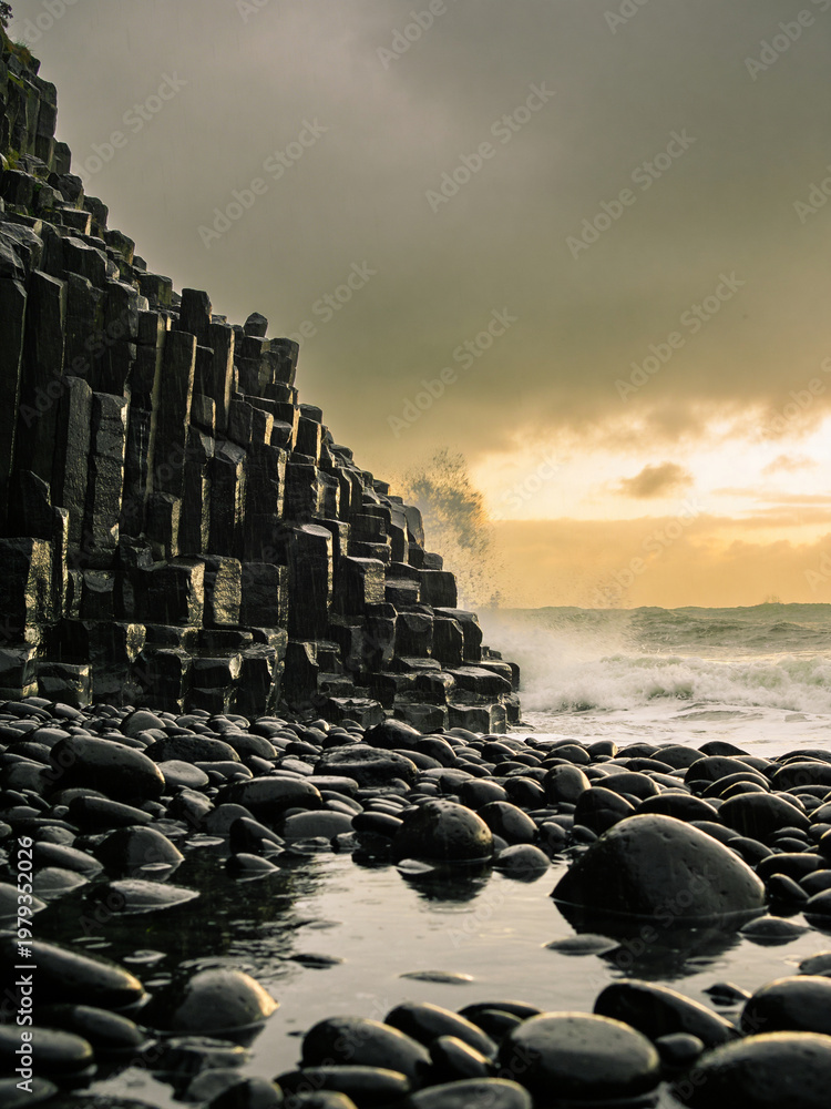 Naklejka premium Atmospheric Basalt Formations Under Dramatic Skies and Ocean Spray