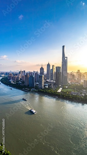 A stunning aerial view captures the modern skyline of Shanghai, China, bathed in the warm glow of a sunset over the Huangpu River.