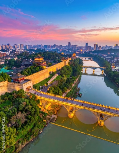 An aerial view showcases the ancient Xi'an City Wall illuminated at dusk, gracefully curving along a river with arched bridges, set against a vibrant sunset and a modern cityscape.