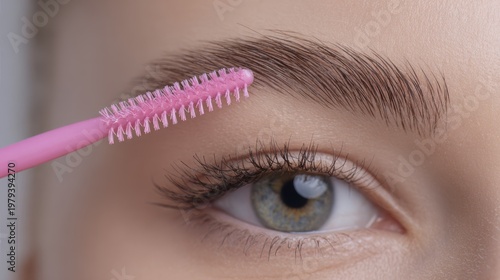 Close-up of eye and eyebrow grooming with pink brush on smooth skin