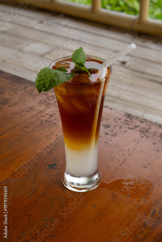 Refreshing layered iced tea mocktail with mint garnish on wooden table