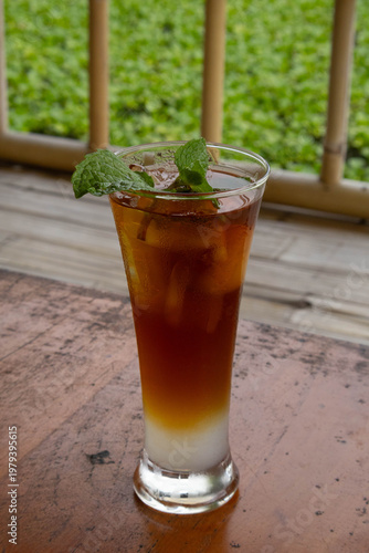 Refreshing layered iced tea mocktail with mint garnish on wooden table