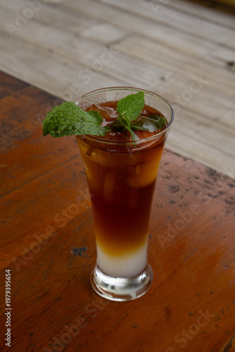 Refreshing layered iced tea mocktail with mint garnish on wooden table