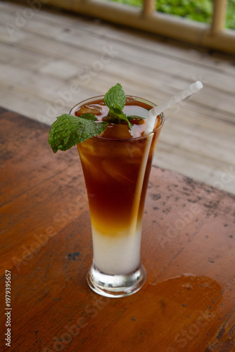 Refreshing layered iced tea mocktail with mint garnish on wooden table