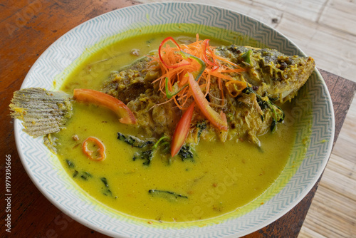 Traditional Indonesian fish dish cooked in yellow turmeric coconut milk sauce