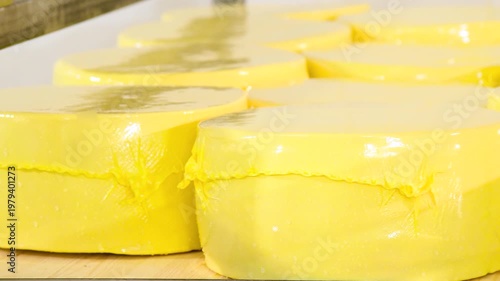 Racks filled with numerous round wheels of yellow cheese.