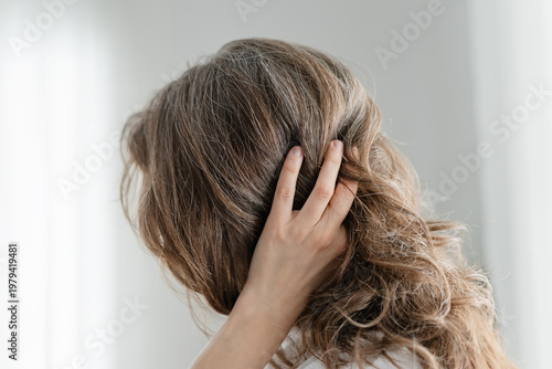 A woman celebrates her natural hair color which includes beautiful gray strands throughout. The mature adult refuses to dye and embraces authenticity completely. Mother loves genuine silver locks