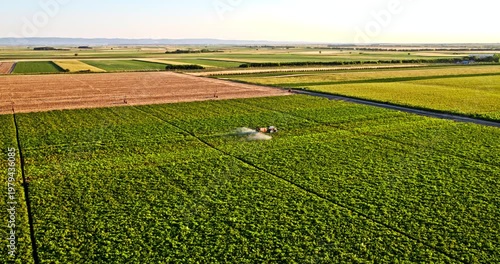Aerial view of tractor spraying pesticides on a green agricultural field