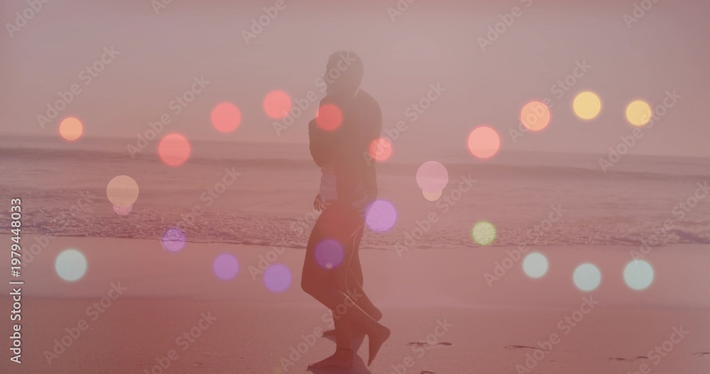 Fototapeta premium Walking couple wearing casual clothes strolling along wet shoreline at sunset, bokeh orbs
