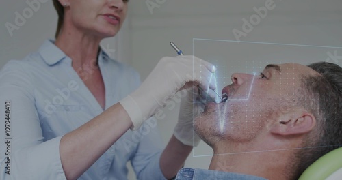 Dentist examining reclining patient in clinic, blue shirt and drill with overlay, copy space