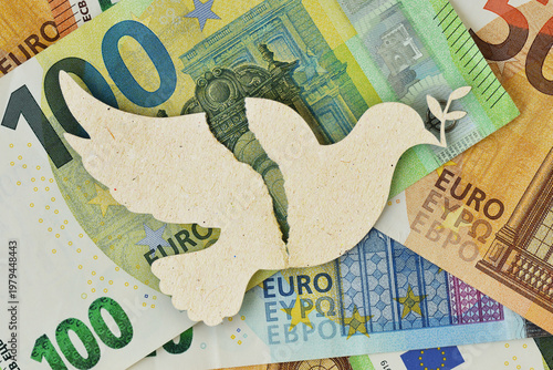 Torn paper dove on euro bankonotes background - Concept of war and economic impact