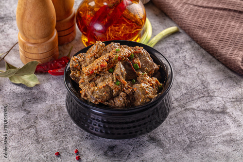 Canvastavla Hearty stewed chicken liver with herbs and spices in a black bowl on a gray table