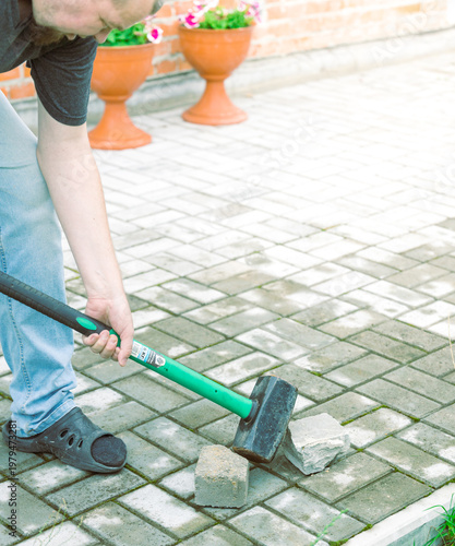 Wallpaper Mural Man breaks stone with sledgehammer on paved walkway Torontodigital.ca