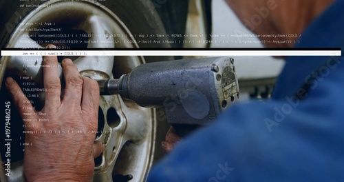 Tightening blue-shirted mechanic operating air impact wrench on wheel rim in workshop, code overlay