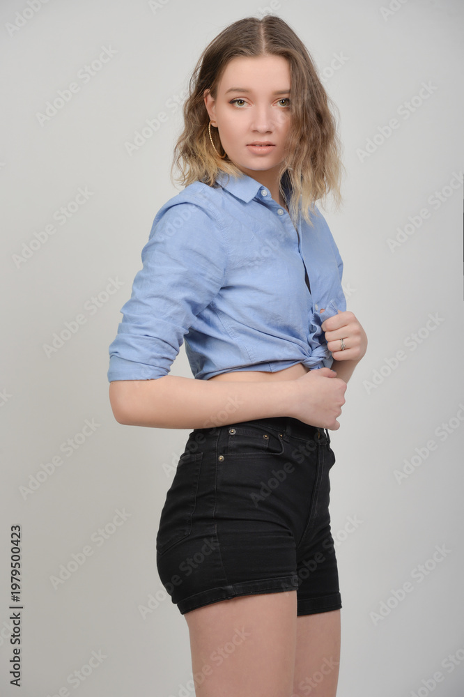 Fototapeta premium Junge Frau im bauchfreien Denim-Outfit, skinny Figur und lässiger Look, nachdenkliche Pose, modernes Fashion- und Lifestyle-Porträt