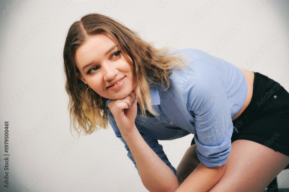 Obraz premium Junge Frau im bauchfreien Denim-Outfit, skinny Figur und lässiger Look, nachdenkliche Pose, modernes Fashion- und Lifestyle-Porträt
