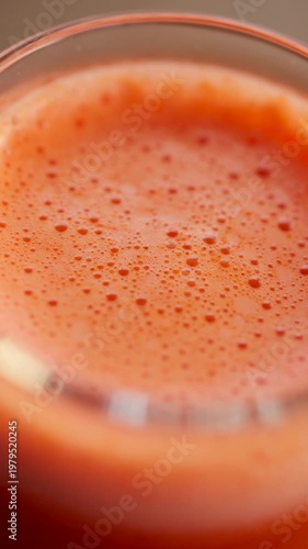Extreme close up of fresh orange juice surface with bubbles and foam texture