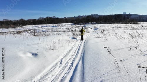 Single Skier On Icy Plains. One Adventurer Skiing Across Snowy Fields Towards Distant Sky. An Independent Skier Journeys Through Winter Wilderness Along Winding Trail Beneath Clear Blue Sky