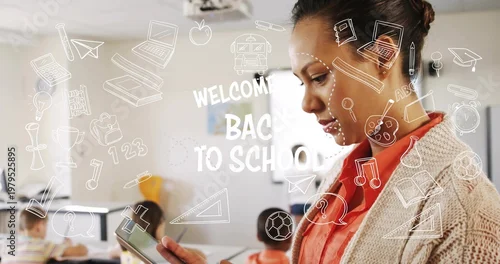 Fototapeta Holding tablet teacher wearing coral top teaching in class with WELCOME BACK TO SCHOOL overlay