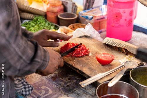 A man cutting tomato slice for spicy puffed rice ingredient
