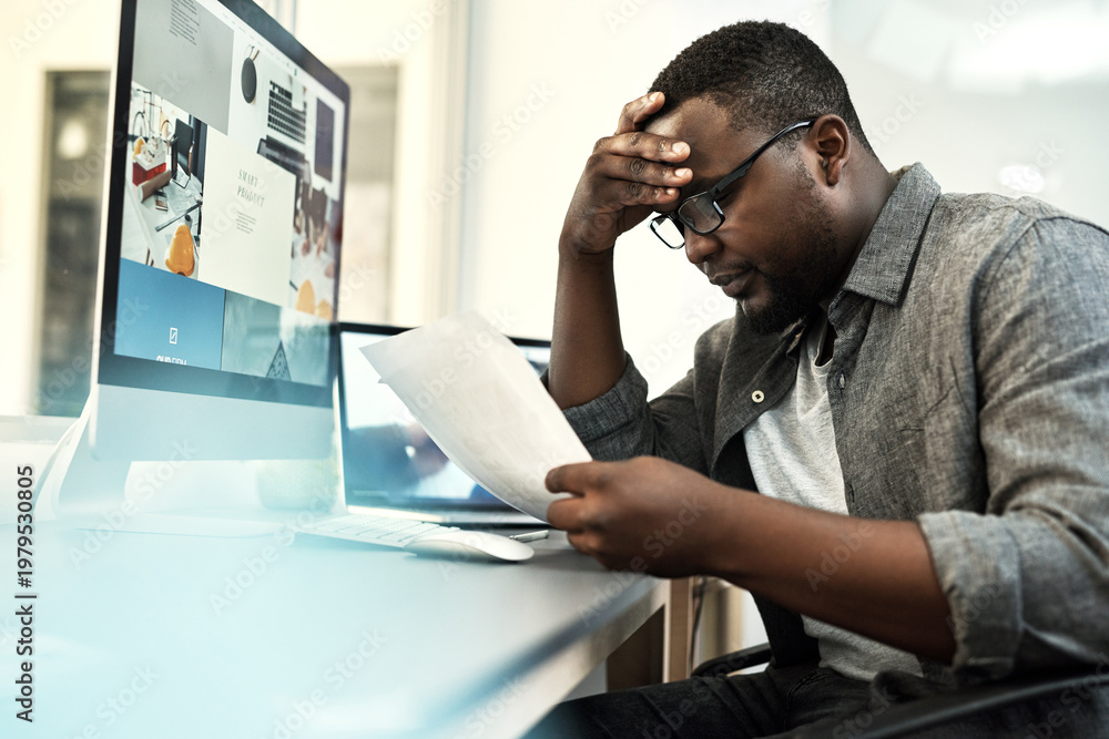 Fototapeta premium Computer screen, documents and stress with web designer black man in office for problem solving. Paperwork, pc and reading with African developer at desk in creative workplace for planning mistake