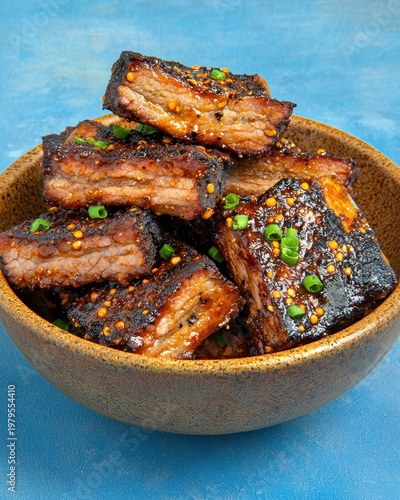 Glazed Barbecue Pork Ribs in Rustic Bowl on Blue Background
