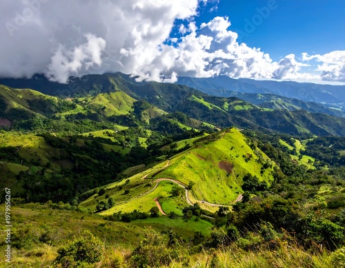 Verdant hills and mountains under a partly cloudy sky. Winding roads weave through the lush green landscape. Shadows enhance the terrain