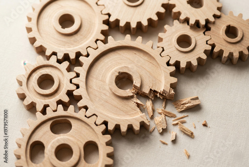 Interlocked wooden gears with missing teeth showing operational failure