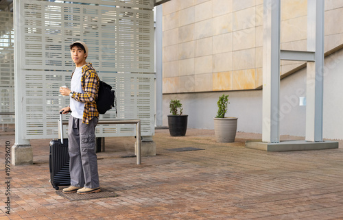 Traveler pausing on plaza waiting for ride, holding cup and suitcase, transit map overlaying scene