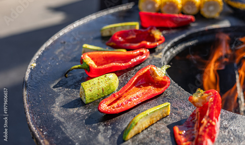 Fotografie Red bell peppers and zucchini being grilled over an open fire