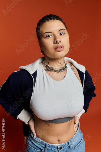 Stylish young woman expressing confidence against a vibrant orange backdrop