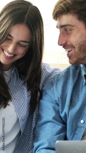 Happy Young Couple Laughing and Smiling While Browsing Content on a Laptop