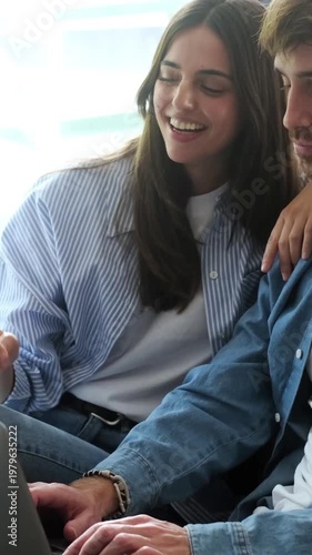 Happy Young Couple Laughing Together While Using a Laptop