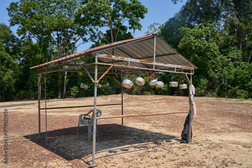 Bilde på lerret A creative art installation featuring various brightly aluminium kettles and teapots hanging from a wire  under zink roof against green forest background